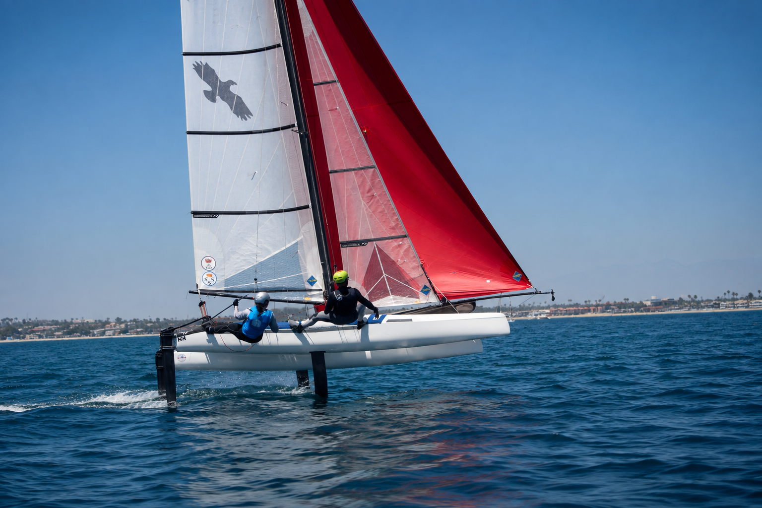 Two sailors foiling on a catamaran with red and white sails